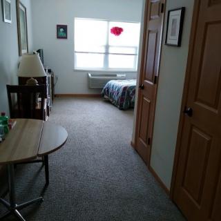 A view of a cozy bedroom with a neatly made bed and natural light coming through the window.