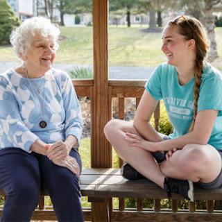 A heartwarming moment between a young woman and an elderly lady enjoying a conversation outdoors.