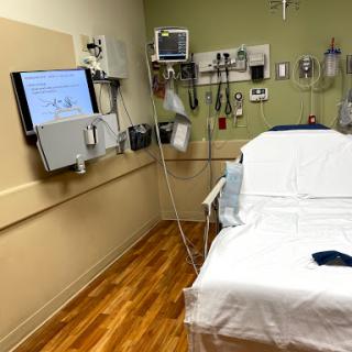 A patient room in a hospital equipped with a bed and medical monitoring devices.
