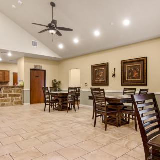 A spacious dining area with tables and chairs, featuring a ceiling fan and artwork on the walls.