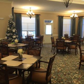 A cozy dining room with tables and chairs, decorated for the holidays with a Christmas tree.