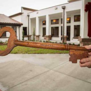 A large ceremonial key held in front of a building.