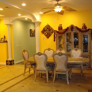 A well-decorated dining room with yellow walls, featuring a table set and chandelier.