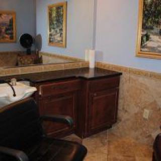 A salon interior featuring a mirror, sink, and decorative artwork.