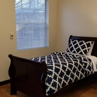 A simple bedroom with a single bed next to a window.
