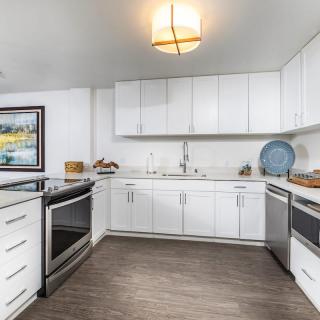 A modern kitchen with white cabinets and stainless steel appliances.