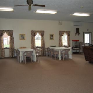 A spacious recreational room with multiple tables and chairs, adorned with decorative curtains.