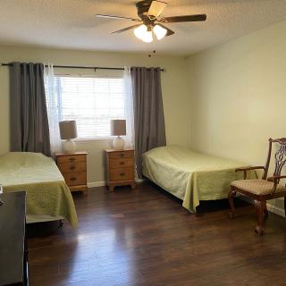 A tidy bedroom with two single beds, nightstands, and a ceiling fan.