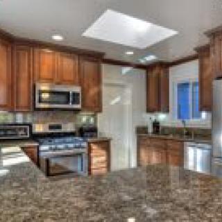 A modern kitchen with wooden cabinets, stainless steel appliances, and a granite countertop.