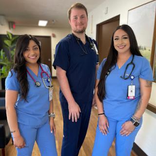 A group of healthcare professionals smiling together in scrubs.