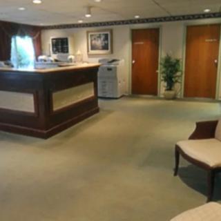 A reception area with a desk, chairs, and a carpeted floor.