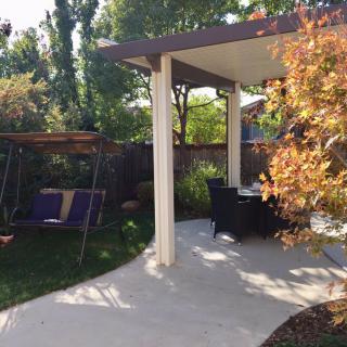 A peaceful backyard with a swing and patio seating surrounded by lush greenery.