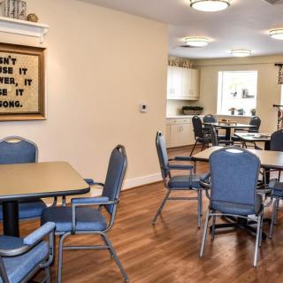 A well-lit dining area with blue upholstered chairs and wood flooring.