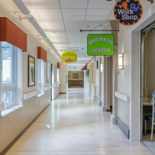 A corridor in a hospital with various signs and bright lighting.