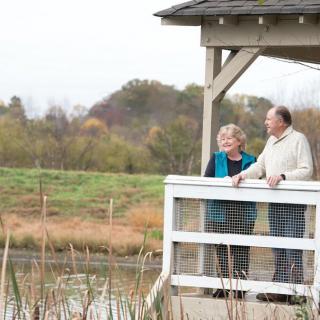 An elderly couple enjoying a peaceful moment in a gazebo overlooking a serene landscape.