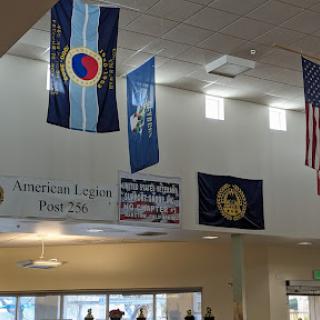 An interior view featuring various flags, including the Colorado state flag and American Legion banner.