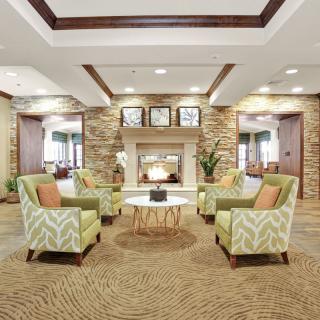 A modern and cozy lobby with a central fireplace, surrounded by comfortable seating and elegant decor.