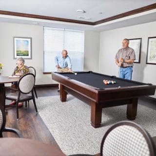 Seniors enjoying a game of billiards in a recreation room.