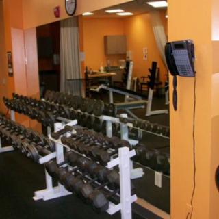 A gym interior featuring a rack of dumbbells and a large mirror.
