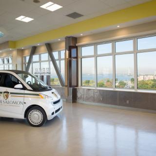 A small hospital vehicle parked inside a modern building with large windows.