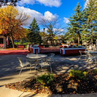 A cozy outdoor patio area surrounded by colorful autumn trees and clear blue skies.