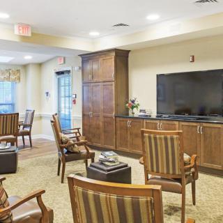 A cozy seating area with wooden chairs and a large television.