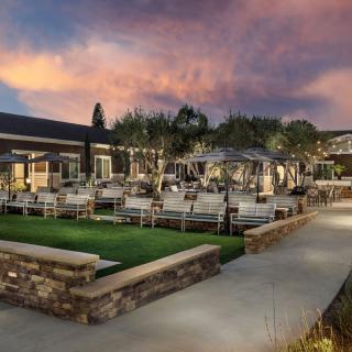 A scenic outdoor patio area with seating, illuminated by lights against a sunset backdrop.