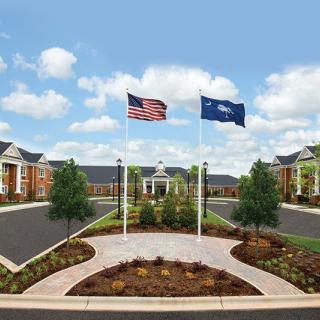 A facility with landscaped surroundings displaying the American and another flag at the entrance.