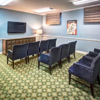 A cozy home theater room with rows of chairs facing a television on the wall.