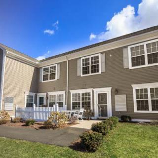 A modern townhouse with a neatly landscaped patio and large windows under a clear blue sky.