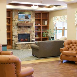 A cozy living room with a stone fireplace, comfortable sofas, and wooden bookshelves.