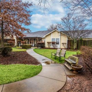 A serene garden path leads to a cozy house surrounded by greenery.