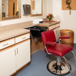 A modern hair salon featuring a red styling chair, mirrors, and clean countertops.