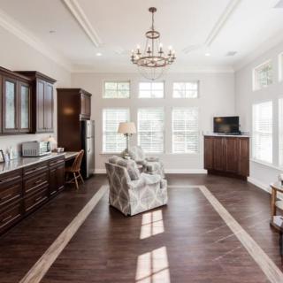 A modern open-concept living room and kitchen with hardwood floors and ample natural light.