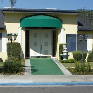 A building entrance with a green awning and well-maintained landscaping.