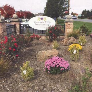 A landscaped garden with colorful flowers and a welcome sign.