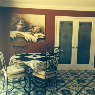 A cozy dining room with a vintage style table and chairs, accented by a decorative painting and patterned floor tiles.