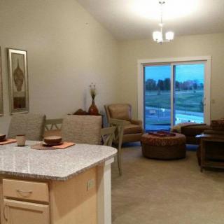 A cozy, modern living room with a kitchen counter and natural lighting from large windows.