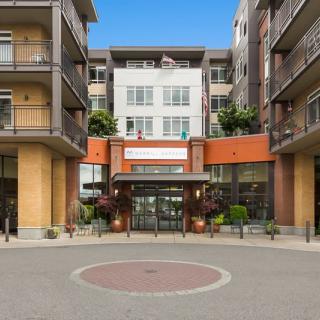 Front view of a modern apartment complex entrance with balconies and greenery.
