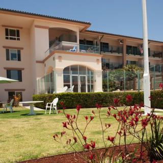 A well-maintained garden in front of a multi-story building with large windows and balconies.