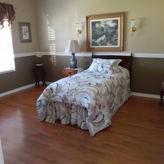 A cozy bedroom with a single bed, lamp, and a painting on the wall.