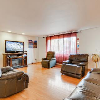 A spacious living room with comfortable leather sofas, a large television, and warm hardwood flooring.