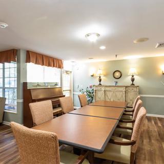 A well-lit dining or meeting area featuring a long table and comfortable chairs, decorated with elegant lighting and furnishings.