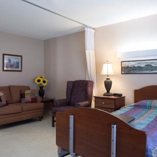 A well-furnished hospital room featuring a bed, sofa, and decorative elements.