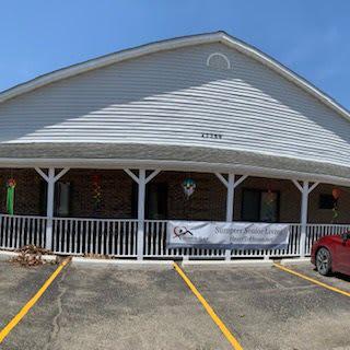 A storefront with a parking lot and a red car parked outside.