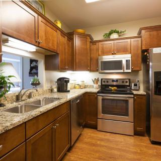 A modern kitchen with wooden cabinets, granite countertops, and stainless steel appliances.