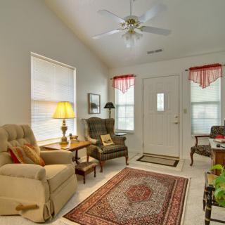 A cozy living room with armchairs, a patterned rug, and a ceiling fan.