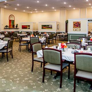 A spacious and elegantly decorated restaurant dining room with neatly arranged tables and chairs.