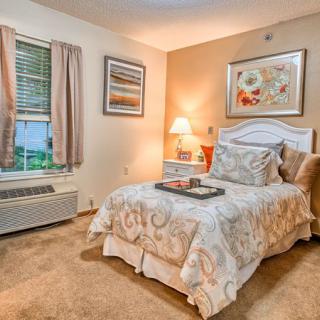 A cozy bedroom with warm lighting, featuring a neatly made bed and elegant decor.
