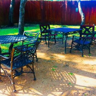 A sunny outdoor patio with tables and chairs set in a garden.